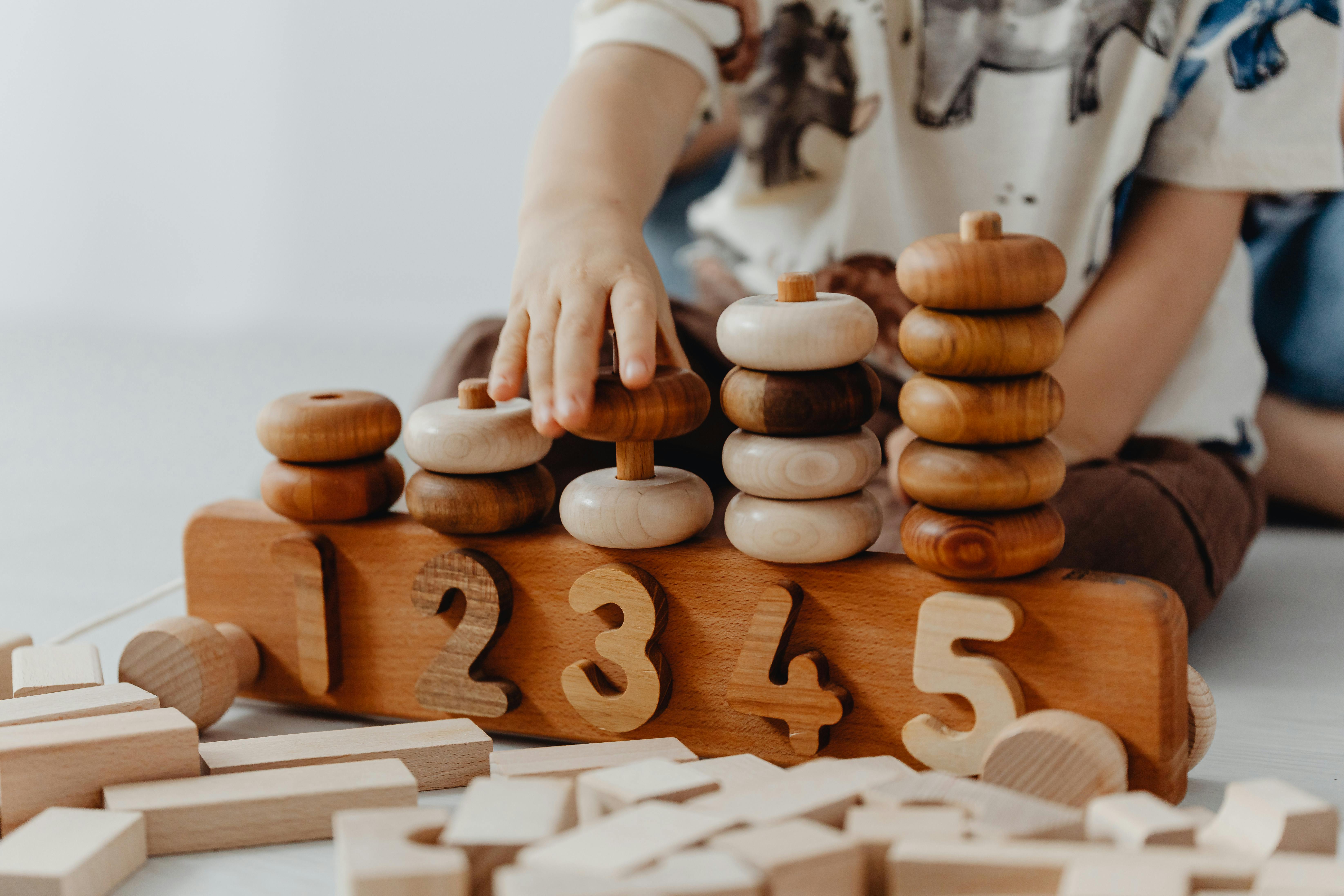Enfant jouant avec un jouet éducatif en bois, illustrant l’accompagnement fiduciaire et stratégique de finidoo pour les institutions de la petite enfance en Suisse romande.